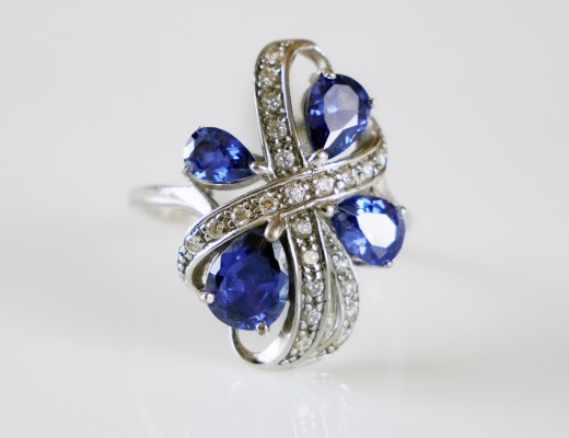 beautiful rich ring with blue tanzanite stones and  many white diamonds on white background